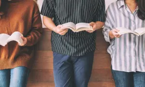 Trzy osoby stojące i czytające książki.