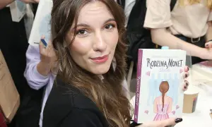 Kobieta trzyma książkę "Rodzina Monet. Skarb" z ilustracją dziewczynki i sylwetek rodziny.