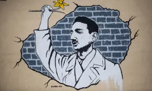 Mural przedstawiający mężczyznę z żółtym żonkilem na tle zniszczonej ceglanej ściany.