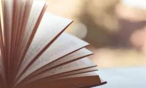 Otwarta książka z rozłożonymi kartkami, widoczne strony z tekstem i numerami.