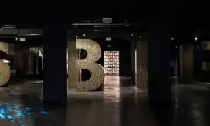 Wielkie litery "S", "Y", "B", "I", "R" w ciemnym wnętrzu, z niebieskimi refleksami na podłodze.
