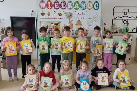 Dzieci trzymające prace plastyczne z wielkanocnymi króliczkami.