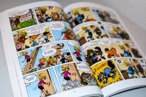 Otwarta książka z kolorowymi ilustracjami komiksowymi, przedstawiającymi postacie i zwierzęta.