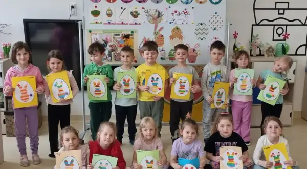 Dzieci trzymające prace plastyczne z wielkanocnymi króliczkami.