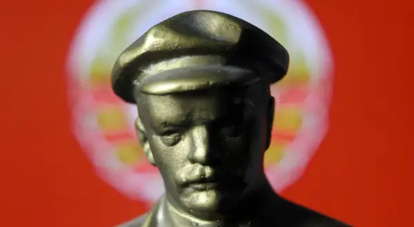 Popiersie mężczyzny w czapce na tle czerwono-białego okręgu.