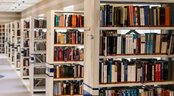Rzędy regałów z książkami w bibliotece.