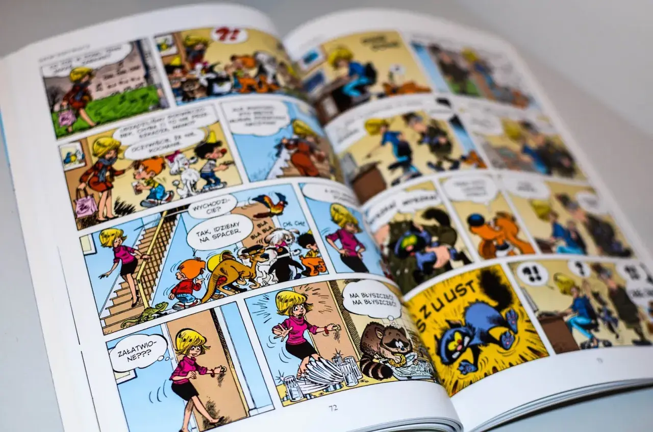 Otwarta książka z kolorowymi ilustracjami komiksowymi, przedstawiającymi postacie i zwierzęta.