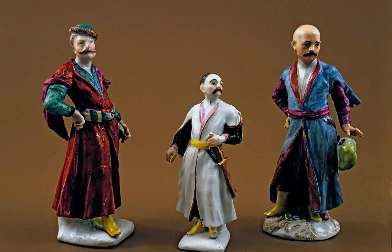 Trzy porcelanowe figurki szlachciców w strojach sarmackich.