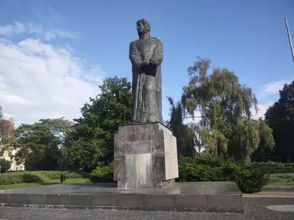 Pomnik Adama Mickiewicza na tle błękitnego nieba i zieleni.
